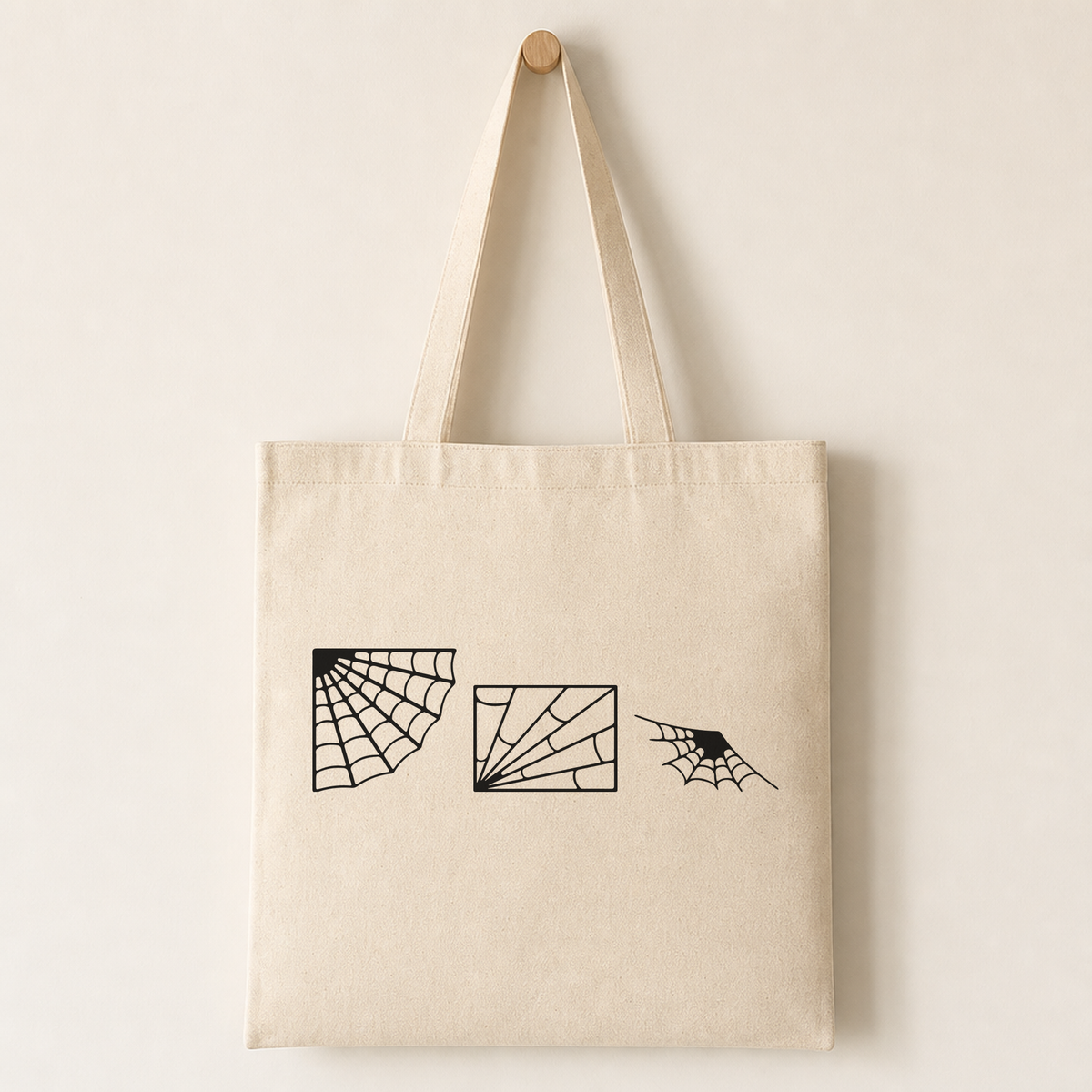 Canvas tote bag printed with a medium-sized spiderweb illustration on one side