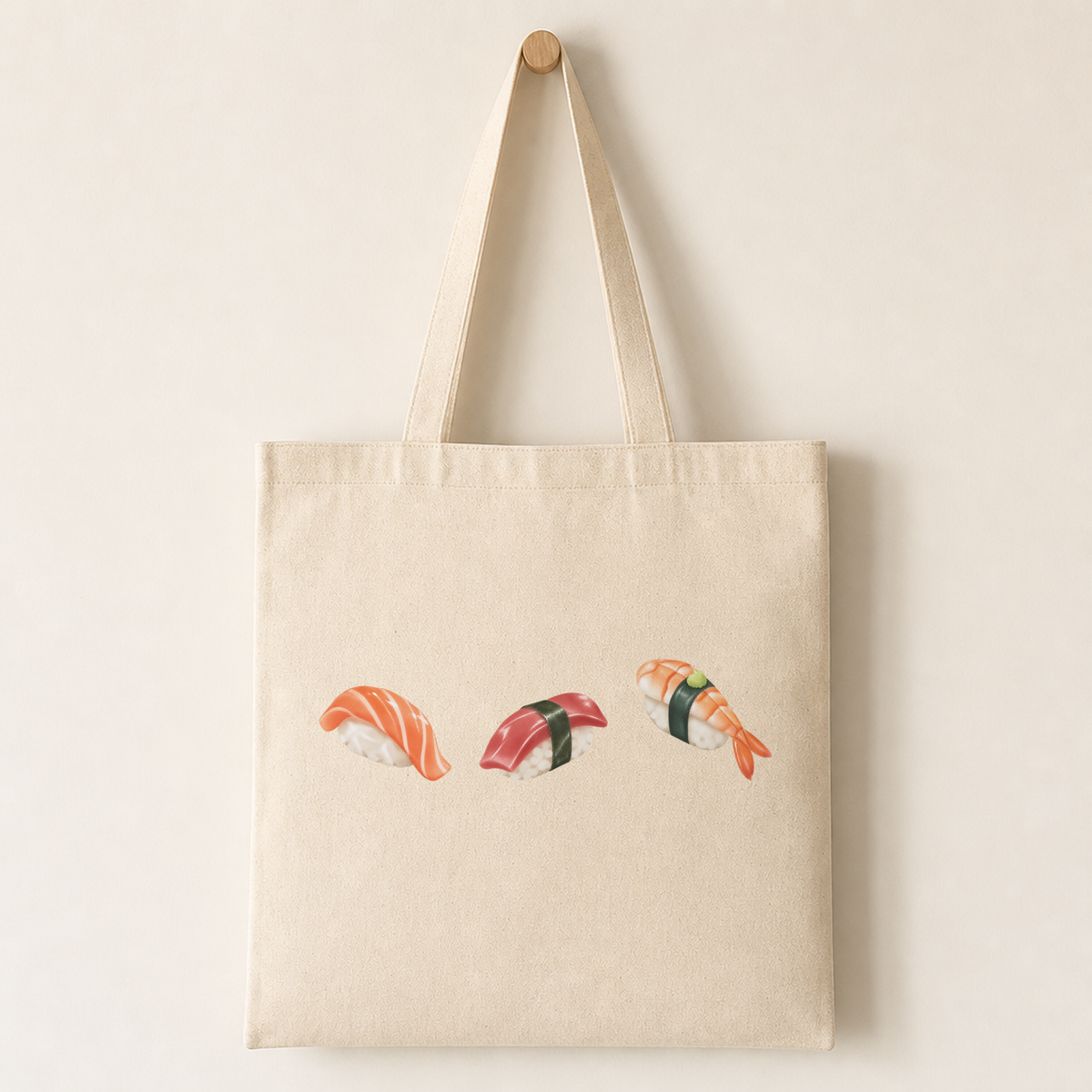 Plain canvas tote bag with several small sushi punctuation characters printed together near the lower half, each with sesame, nori and ginger details.