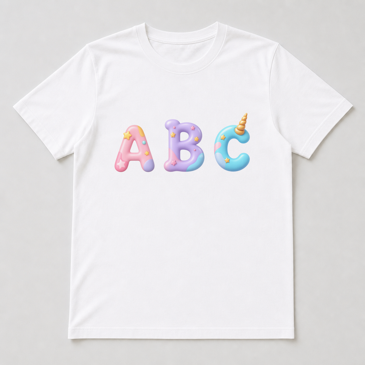 White t-shirt mock-up with a unicorn-themed capital letter printed on the chest showing the gold horn, pastel rainbow tuft and sparkles.